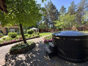 a large black trash can next to a tree and benches at House By The Sea With Hot Tub in Rīga