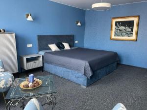 a blue bedroom with a bed and a table at Targaleseta guest house in Ventspils