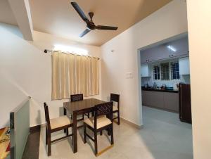 a dining room with a table and chairs and a kitchen at Namasvi 2Bedroom AC House in Narasimharaja Puram