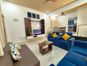 ein Wohnzimmer mit blauen Sofas und einem Fernseher in der Unterkunft Namasvi 2Bedroom AC House in Narasimharaja Puram