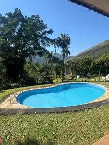 a blue swimming pool in the grass with a mountain in the background at Recanto do Bosque in Magé