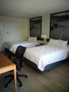 two beds in a hotel room with a desk and a chair at MHO Hotel Dover in Dover