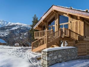 a log cabin with a deck in the snow at Chalet moderne à Méribel avec jacuzzi et sauna - FR-1-566-30 in Les Allues