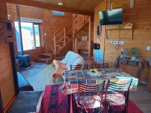 a dining room with a table and a television in a cabin at La Morada del Lago in Tolhuin