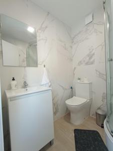 a white bathroom with a toilet and a sink at Estudios Diego in Puerto de Sagunto