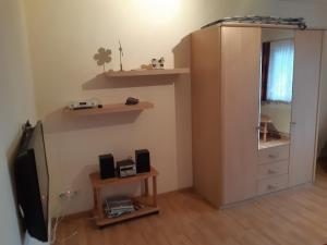 a living room with a tv and a dresser and a mirror at Ferienwohnung Schwarzwaldblick in Steingrün