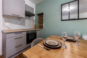 レンヌにあるLe Nid du Graverandのキッチン(木製テーブル、ワイングラス付)