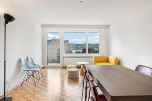 a living room with a table and chairs and a window at EXQUIS Design 3-Room Apartment KNOLL I Zurich Lake View I Balcony I Family-Friendly in Männedorf