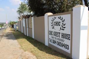 a sign for a coast guest house on a fence at Chic Guest House Alberton in Alberton