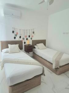 two beds in a bedroom with white walls at Villa Mar in Punta Cana