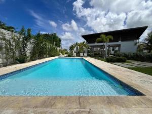 a swimming pool with blue water in front of a house at Villa Mar in Punta Cana