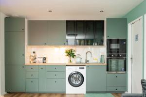 莱克朗兰比塞特尔Paris Homestay of Dreams的厨房配有绿色橱柜和洗衣机。