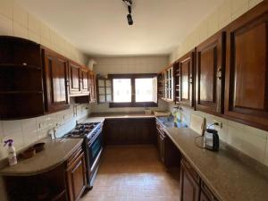 a large kitchen with wooden cabinets and a window at A private room by the rooftop in Cairo