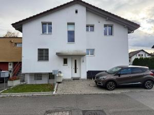 a car parked in front of a white house at Swiss Suites Oberentfelden in Oberentfelden