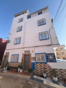 a white building with blue shuttered windows on it at Surf capitain in Tamraght Ouzdar