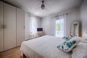 a white bedroom with a large bed and a window at Molo Trovna Apartments in Vis