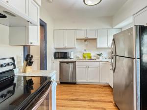 a kitchen with white cabinets and a stainless steel refrigerator at Relaxing 6 -bedroom Escape Near Ingersoll Avenue in Des Moines