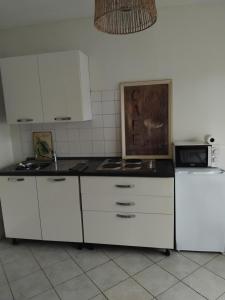 une cuisine avec des armoires blanches et un comptoir noir dans l'établissement Le gîte de Christine, à Lagarde