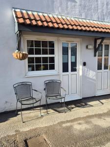two chairs sitting in front of a building with a door at Heads In Beds, The Bull Room NEW LOCATION Vale of York, Carlton Miniott, Thirsk NOT in Thirsk