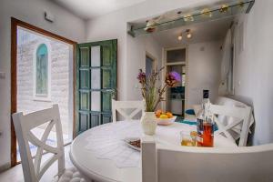 a white dining room with a white table and chairs at Molo Trovna Apartments in Vis