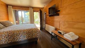 a bedroom with a bed and a tv on a wall at Verdevida Apart Hotel in Pucón