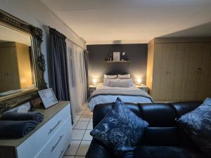a bedroom with a bed and a couch and a mirror at Opal's Rest in Nelspruit