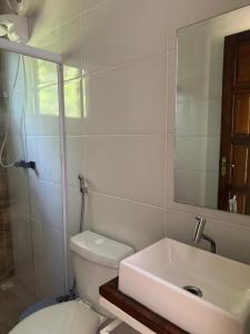 a bathroom with a sink and a toilet and a mirror at Recanto do Bosque in Majé