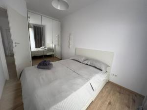 a white bedroom with a large bed and a mirror at Elite Apartments Bucharest in Văleni