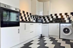 eine Küche mit weißen Schränken und einem schwarz-weiß karierten Boden in der Unterkunft 3-Bedroom House in Warrington with Free Parking Ideal for Contractors and Family Stays in Warrington + 4 Fotos
