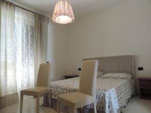 1 dormitorio blanco con 1 cama y 2 sillas en Villa Boemia - apartment, en Coriano