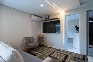 a living room with a couch and a tv at Loft c Varanda, Piscina e Academia em Itacuruca in Itacuruçá +34 photos