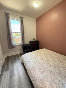 a bedroom with a bed and a chair and a window at Second Floor Apartment in Victorian House in Strathroy