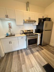 a kitchen with white cabinets and a stove and refrigerator at Second Floor Apartment in Victorian House in Strathroy