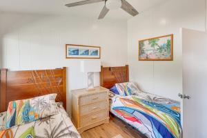 a bedroom with two beds and a dresser and a fan at Steps to Poipu Beach Home with Deck and Scenic View in Koloa