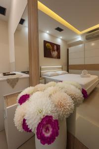 a vase filled with white and purple flowers in a bedroom at Jacuzzi Escape in Tirana