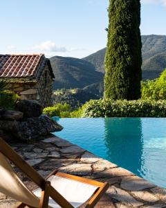 a chair next to a swimming pool with mountains in the background at Mas de la Costete in Mons