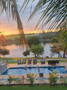 a group of people sitting in a swimming pool next to a lake at Pousada Ana Maria in Delfinópolis