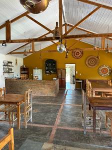 une salle à manger avec des tables en bois et un bar dans l'établissement Pousada Ana Maria, à Delfinópolis
