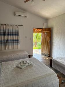 a bedroom with two beds and a door to a yard at Pousada Ana Maria in Delfinópolis +50 photos
