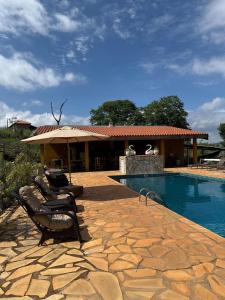 un patio avec des chaises et une piscine avec un bâtiment dans l'établissement Pousada Ana Maria, à Delfinópolis