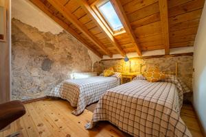 two beds in a room with a stone wall at La Casa de Mi Madre casa rural con jacuzzi in La Parrilla +29 photos