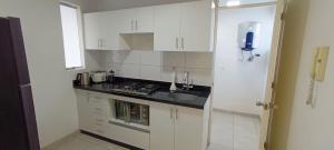a kitchen with white cabinets and a black counter top at Departamento con cochera - Condominio Las Flores in Ica