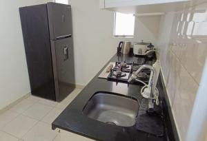 a kitchen with a sink and a black refrigerator at Departamento con cochera - Condominio Las Flores in Ica