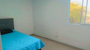 a bedroom with a blue bed and a window at Departamento con cochera - Condominio Las Flores in Ica