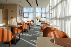 Un comedor con mesas y sillas y ventanas. en MH HOTEL Nouakchott, en Nouakchott