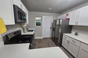 Una cocina con gabinetes blancos y una estufa negra. en Charming 4br Bundle Near Downtown & Airport, en Austin