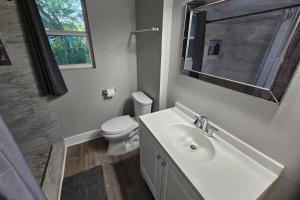 Un baño con lavabo, inodoro y espejo. en Charming 4br Bundle Near Downtown & Airport, en Austin