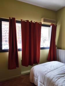 a bedroom with red curtains next to a bed at Libertador 4 MVD in Montevideo