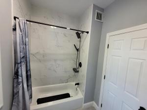 een witte badkamer met een douche en een bad bij The Happy Place in Brockton +5 foto's