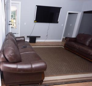 een woonkamer met een leren bank en een flatscreen-tv bij The Happy Place in Brockton